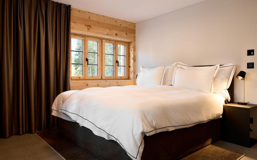 Grosses Bett mit wisser Bettwäsche in einem Holzhaus.