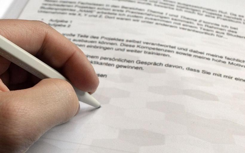 Person unterschreibt Bewerbungsbrief