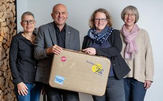 Marianne und David Bühler übergeben den an«Backpackers Villa Sonnenhof»-Koffer an die neue Gastgeberin Isabelle Gruner und ihre Stellvertreterin Catherin Quirin (v.l.).