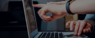 Hände von zwei verschiedenen Personen sind vor einem Laptop sichtbar