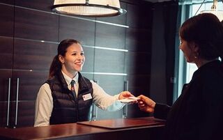 Hoteliere bedient zwei Personen an einem Tresen