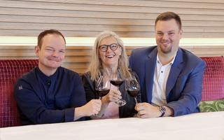 Drei Personen die mit einem Glas Rotwein anstossen