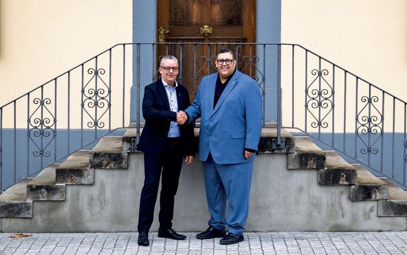 Zwei Personen schütteln sich die Hände vor einer Treppe