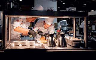 Zwei Köche bereiten ein Gericht vor. 