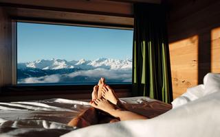 Personen liegen in einem Bett und geniessen Aussicht auf Bergpanorama