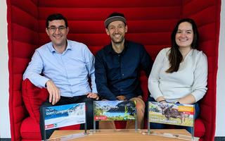 Drei Personen sitzen auf einem roten Sofa