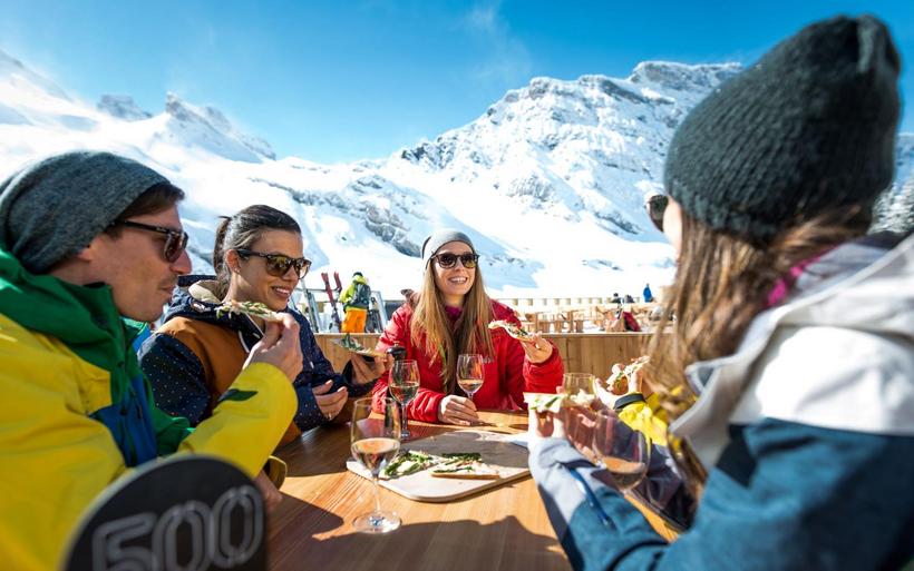 Menschen in Winterkleidung sitzen an einem Tisch draussen.