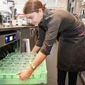 Eine junge Frau beländt einen Gastronomie-Geschirrspüler